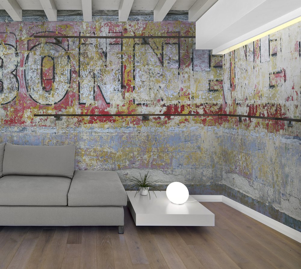 on the wall of this living room is a wallpaper representing an old advertisement of aperitif painted on the wall