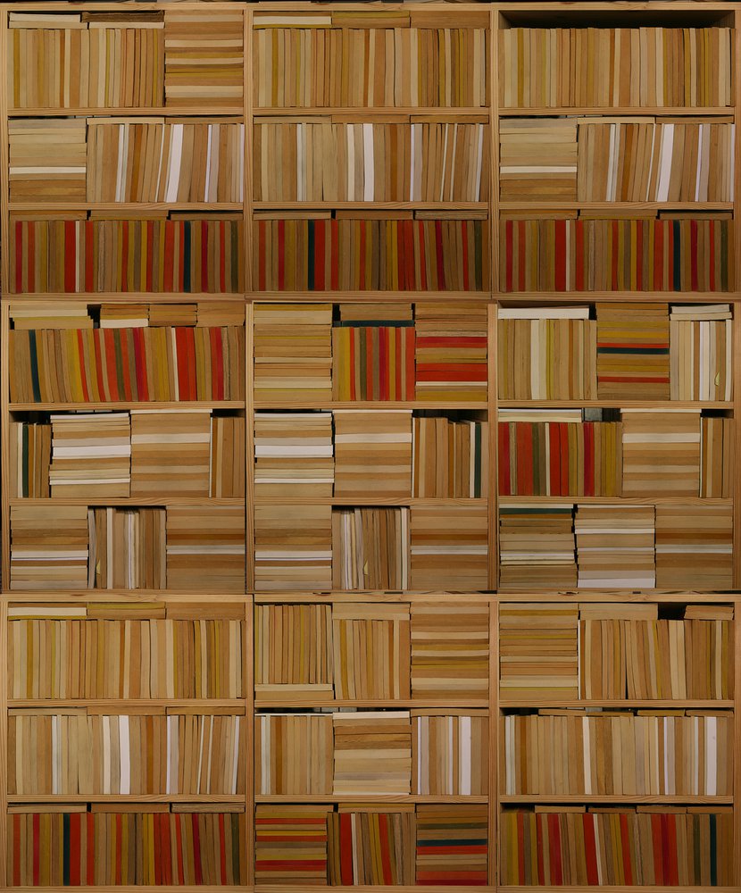 on the wall of this library is an original wallpaper representing a stack of books forming an original geometric composition